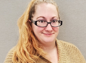 Woman with red blonde hair and glasses smiling